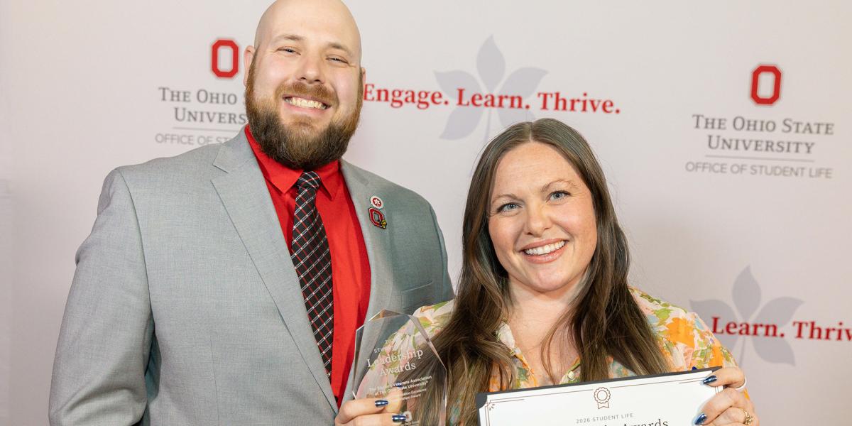 Two people smiling at the camera with one holding an award and a certificate